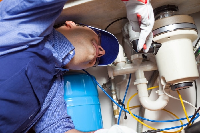 A plumber checking on a garbage disposal unit