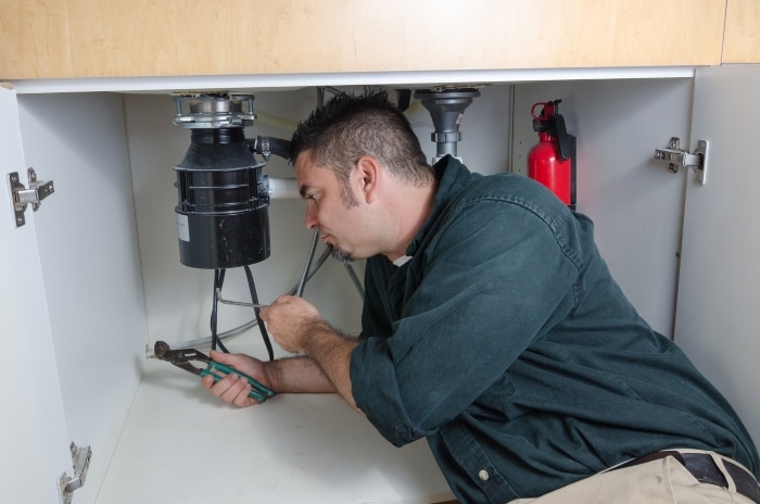 A plumber checking a garbage disposal unit