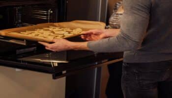 A man placing cookies inside an oven
