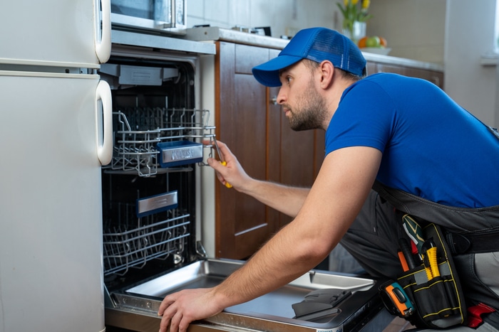 A technician checking the inside of a dishwasher