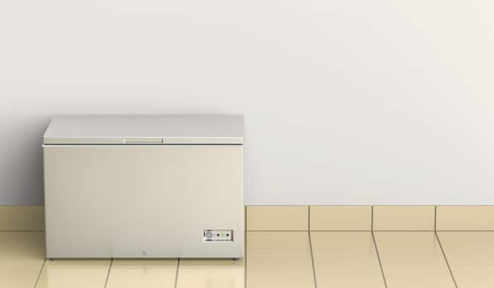 A chest freezer on a white background with tiles