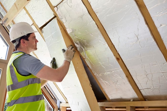A man insulating a home's walls
