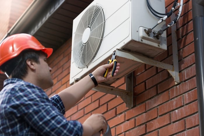 A technician checking the exterior side of a through-the-wall Air Conditioner