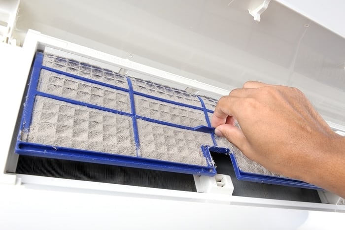 A person cleaning an Air Conditioner's dirty air filters