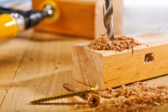 A wooden board being drilled