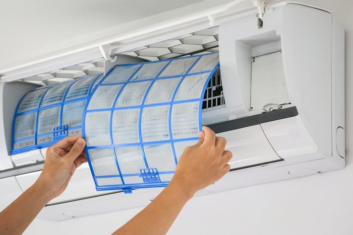 A person removing the filters of an Air Conditioner
