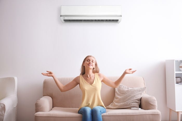A young woman sitting under an Air Conditioner