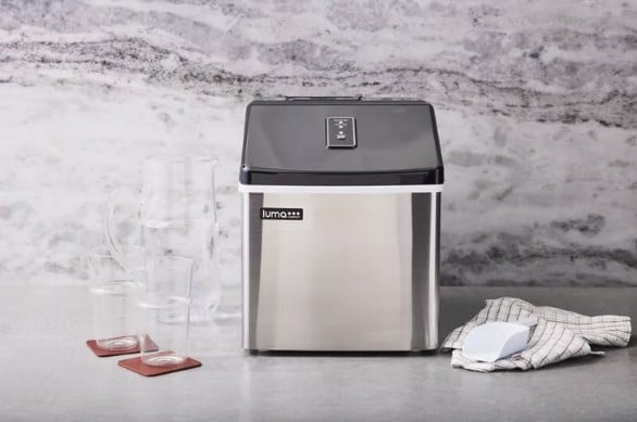 A countertop ice maker with glasses on the side