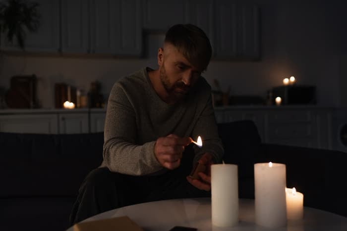 A man next to several lit candles in the dark