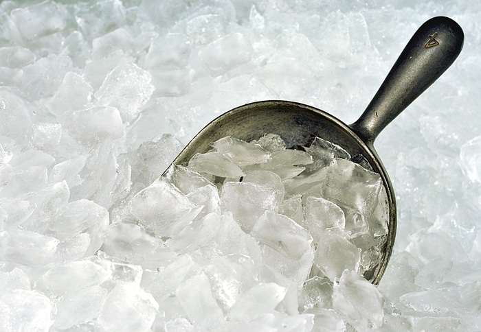 A pile of ice and a metal shovel in an ice maker 
