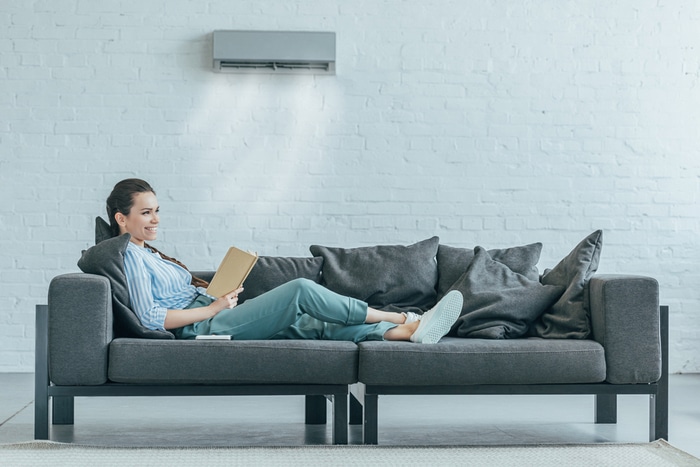 A woman reading under her Air Conditioner