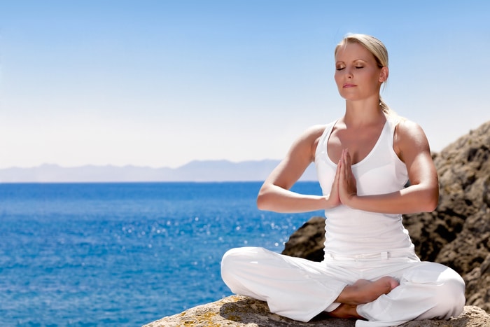 A woman meditating near the shoreline