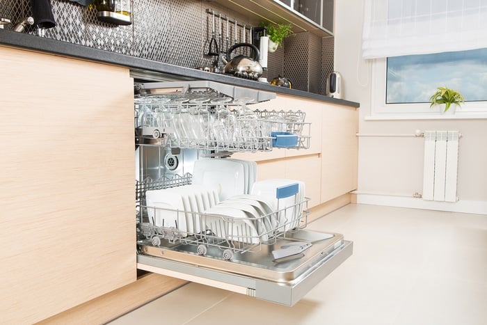 An open dishwasher in a light-colored kitchen
