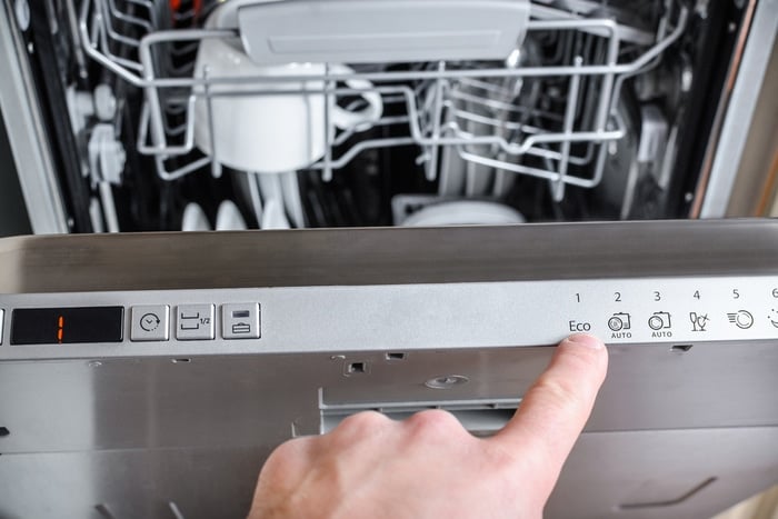 A person dialing in settings on a dishwasher