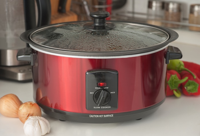 A red slow cooker with the lid on
