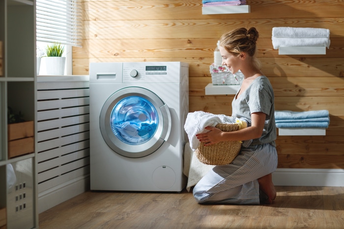 A woman placing clothes inside a washer