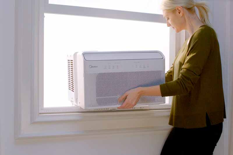 Woman installing U-shaped window air conditioner