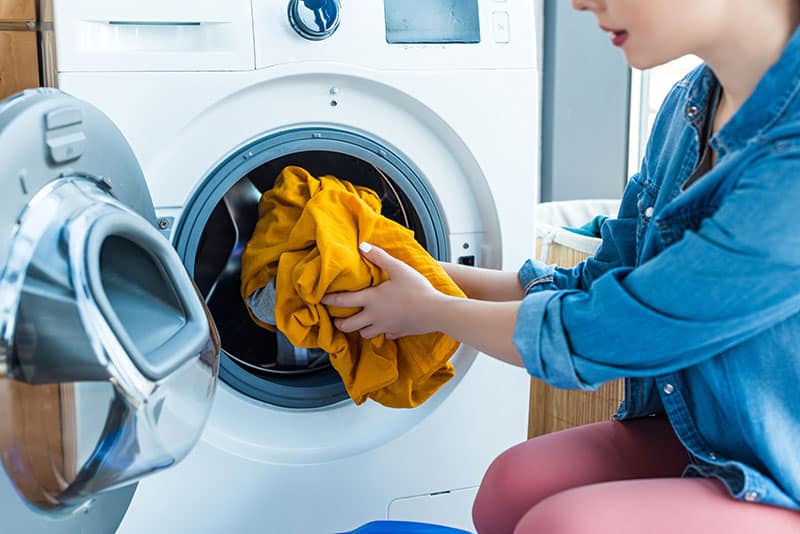 woman putting washing into washing machine