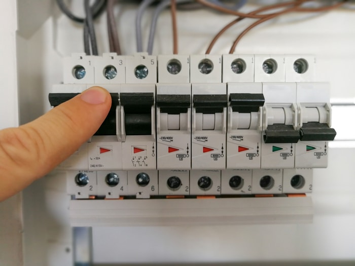 A person adjusting the switches on a circuit breaker