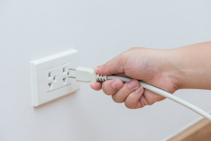 A person plugging something into a wall outlet