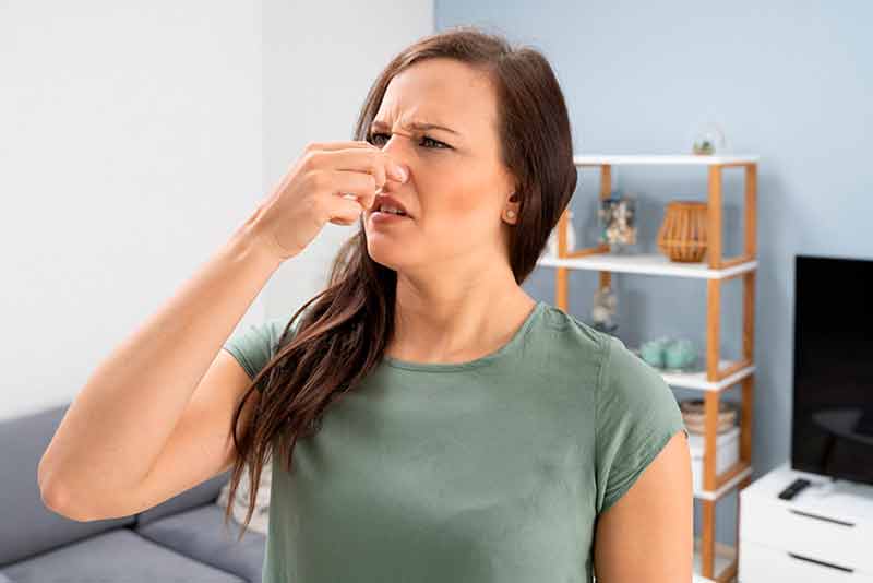 Woman covering her nose due to the burnt smell coming from her window air conditioner