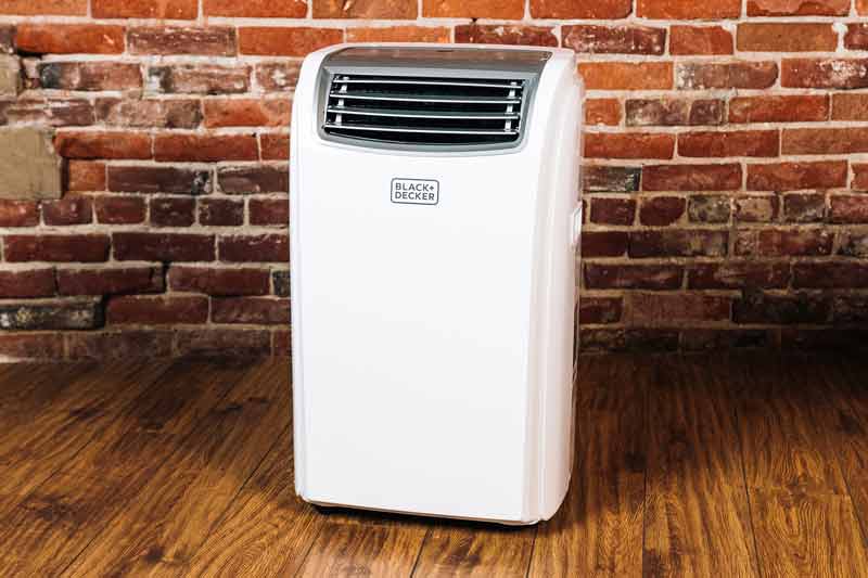portable air conditioner with a brick wall in the background.