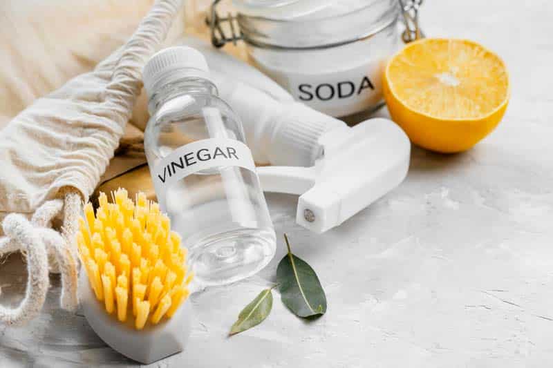 cleaning kit consisting of baking soda vinegar lemon a brush and a spray bottle