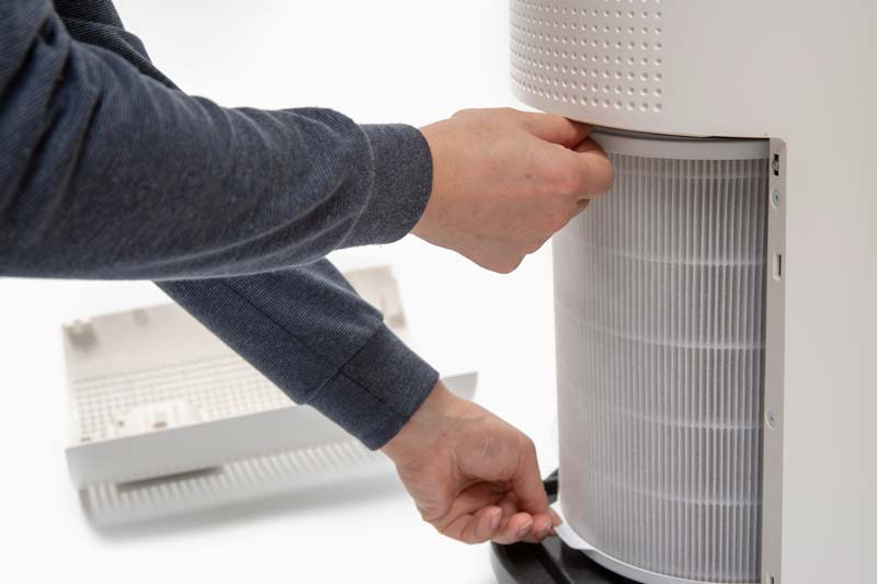 Hands removing the back cover of a portable air conditioner