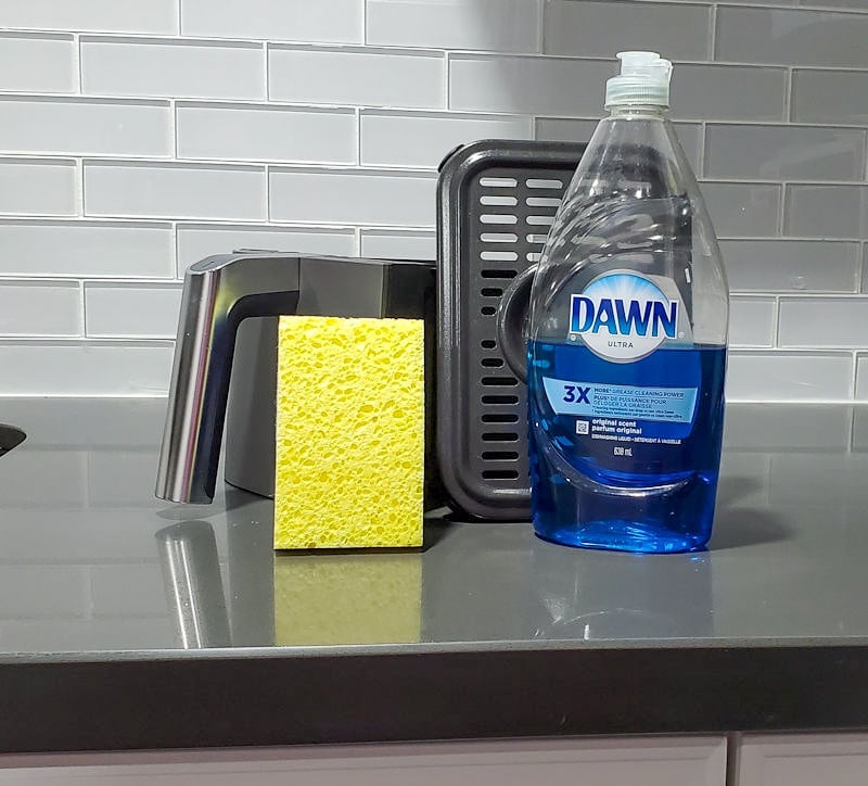 Sponge and detergent next to air fryer basket