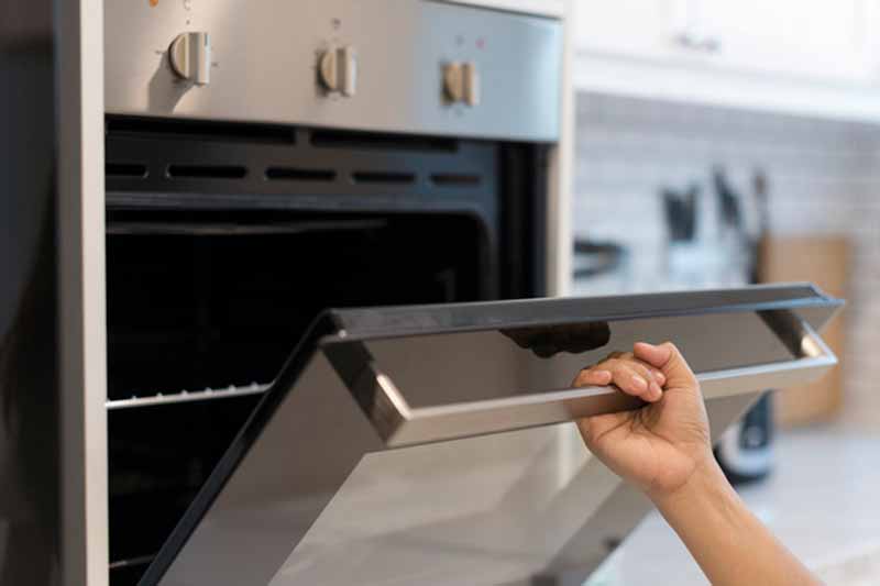 Side View Of Hand Opening Oven
