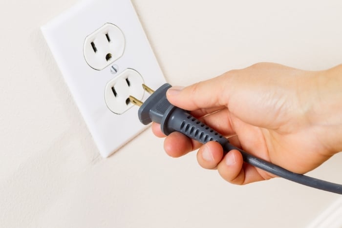 Person disconnecting cable from wall outlet