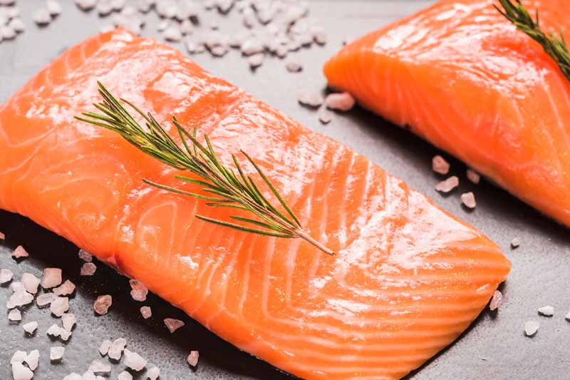 Piece of raw salmon with rosemary and coarse salt