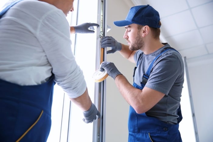 Technicians insulating a window frame