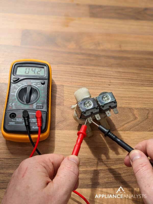 Testing a washer's water inlet valve with a multimeter.