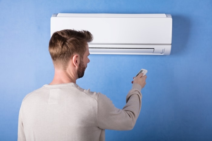 Man changing the settings of his AC via remote