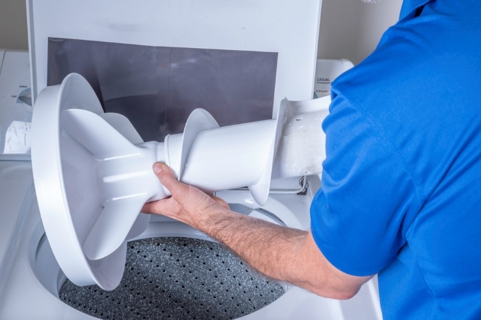 A man checking a washer agitator