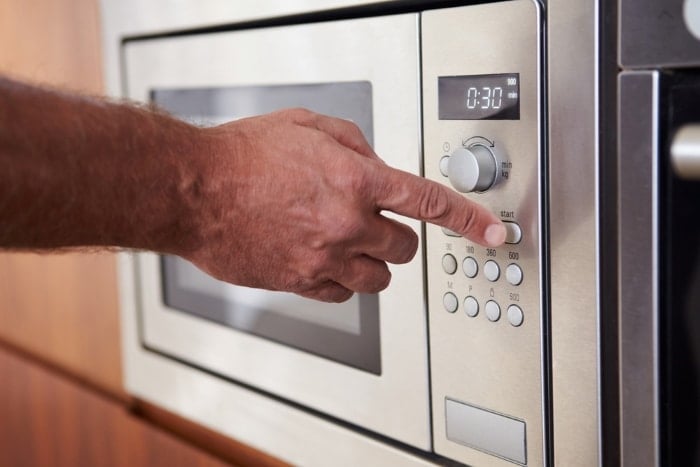 Person pressing microwave oven buttons