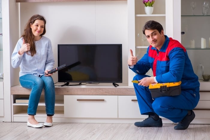 TV technician with woman in a living room